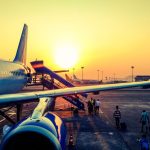 Passageiros embarcam em um avião ao amanhecer.