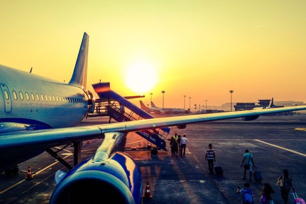 Passageiros embarcam em um avião ao amanhecer.