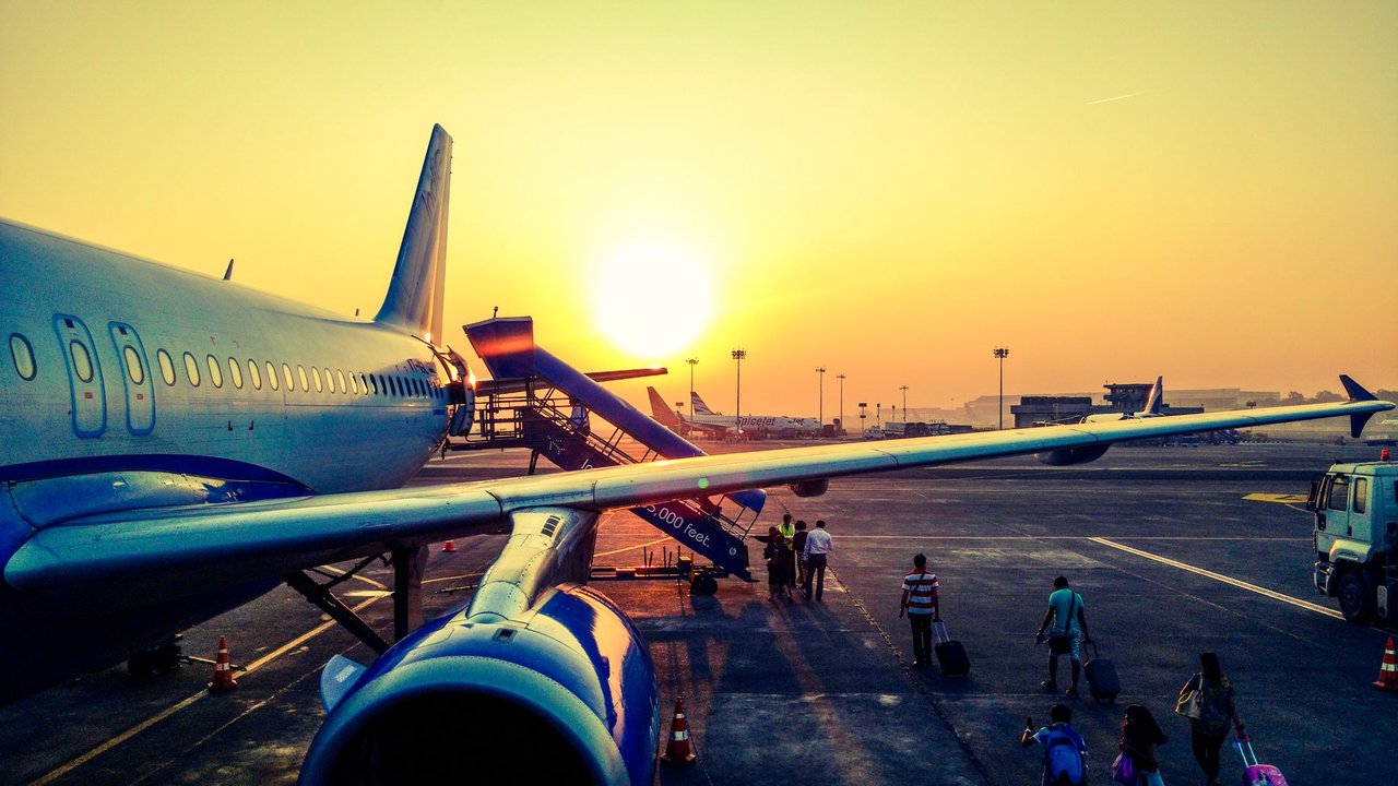 Passageiros embarcam em um avião ao amanhecer.