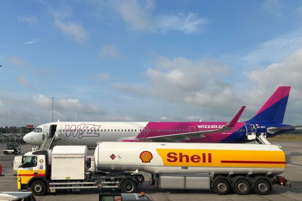 Avião comercial sendo abastecido por um caminhão-tanque da Shell no pátio de um aeroporto.