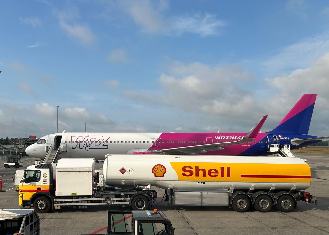 Avião comercial sendo abastecido por um caminhão-tanque da Shell no pátio de um aeroporto.