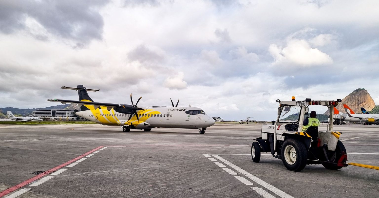 Avião turboélice na pista de um aeroporto do Rio de Janeiro, com equipe de solo ao redor.