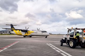 Avião turboélice na pista de um aeroporto do Rio de Janeiro, com equipe de solo ao redor.